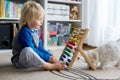 Cute preschool child, playing with abacus at home, little pet dog playing around