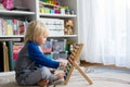 Cute preschool child, playing with abacus at home, little pet dog playing around