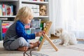 Cute preschool child, playing with abacus at home, little pet dog playing around