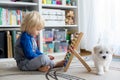 Cute preschool child, playing with abacus at home, little pet dog playing around Royalty Free Stock Photo