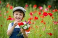Cute preschool child in poppy field, holding a bouquet of wild flowers Royalty Free Stock Photo