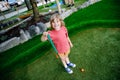 Cute preschool girl playing mini golf with family. Happy toddler child having fun with outdoor activity. Summer sport Royalty Free Stock Photo