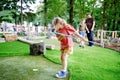 Cute preschool girl playing mini golf with family. Happy toddler child having fun with outdoor activity. Summer sport Royalty Free Stock Photo