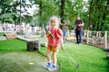 Cute preschool girl playing mini golf with family. Happy toddler child having fun with outdoor activity. Summer sport Royalty Free Stock Photo