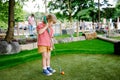 Cute preschool girl playing mini golf with family. Happy toddler child having fun with outdoor activity. Summer sport Royalty Free Stock Photo