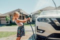 Girl washing car on driveway in front house on sunny summer day Royalty Free Stock Photo