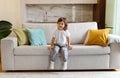 Cute preschool little girl sitting on couch at home, smiling at camera