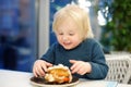 Cute preschooler boy eating large hamburger at fast food restaurant. Unhealthy meal for kids. Junk food. Overweight problem child