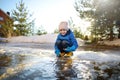 Cute preschooler boy is playing with a stick in brook on sunny day. Child having fun and enjoy a big puddle. All kids love play Royalty Free Stock Photo