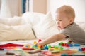 Cute preschooler child boy plays with mosaic at home. A blond little toddler playing in kid`s room. Leisure activities Royalty Free Stock Photo