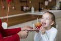 Cute preschooler girl celebrating 6th birthday. Mother giving daughter birthday cupcake with a candle. Childrens birthday party.