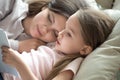 Cute little girl lying in bed with mom reading book Royalty Free Stock Photo