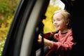 Cute preteen boy looking out through window of car during family road trip and enjoy of pleasant expectation of happy vacation. Royalty Free Stock Photo