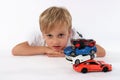 Cute preteen boy lying with a pile of car toys and making a confused look in his face