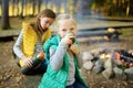 Cute preteen girl drinking tea and roasting marshmallows on stick at bonfire. Child having fun at camp fire. Camping with children Royalty Free Stock Photo