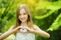 Cute preteen girl laughing and holding her hands in a heart shape on bright and sunny summer day. Cute child enjoying herself outd Royalty Free Stock Photo