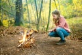 Cute preteen girl roasting marshmallows on stick at bonfire. Child having fun at camp fire. Camping with children in fall forest Royalty Free Stock Photo