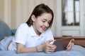 Cute preteen girl smile lying on sofa looking at digital tablet pad