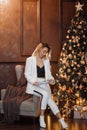 A cute pretty blonde woman in a white suit plans new year and Christmas holidays writes a plan in a notebook, a