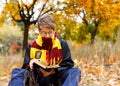 Cute pretty boy in costume of Harry Potter and scarf plays as a magician, reads book in autumn