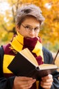 Cute pretty boy in costume of Harry Potter and scarf plays as a magician, reads book in autumn