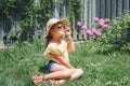 Cute pretty preteen child girl in sunglasses and straw hat sitting on grass outdoor. Happy smiling Caucasian kid having fun at Royalty Free Stock Photo