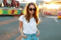 Cute pretty stylish hipster young woman in vintage jeans in fashionable sunglasses in a white stylish t-shirt walks