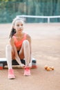 A cute, pretty teenage girl sits on a step platform and relaxes after her workout on outdoor