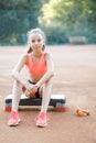 A cute, pretty teenage girl sits on a step platform and relaxes after her workout on outdoor