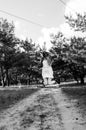 Cute and pretty young blond girl in white dress, jeans jacket and black boots jumping on the sand road Royalty Free Stock Photo