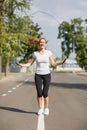 Cute and pretty young girl exercising with a jumping rope on a park background. Gymnastics concept. Royalty Free Stock Photo