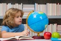 Cute pupil looking at globe in library at the elementary school. School child. Kid boy from elementary school. Pupil go Royalty Free Stock Photo