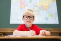 Cute pupil smiling at camera in classroom at his desk Royalty Free Stock Photo