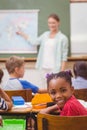 Cute pupil smiling at camera at his desk in classroom Royalty Free Stock Photo