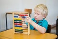 Cute pupil using abacus in classroom