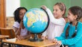 Cute pupils sitting in classroom with globe