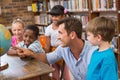 Cute pupils and teacher looking at globe in library Royalty Free Stock Photo