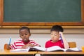 Cute pupils writing at desk in classroom