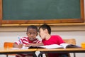 Cute pupils writing at desk in classroom