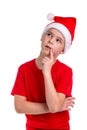 Cute puzzled looking boy, santa hat on his head, with the finger near the lips. Concept: christmas or Happy New Year Royalty Free Stock Photo