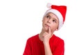 Cute puzzled looking boy, santa hat on his head, with the finger near the lips. Concept: christmas or Happy New Year Royalty Free Stock Photo