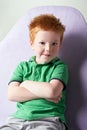 Cute red haired freckled little boy in green t-shirt waiting for doctor in medical office Royalty Free Stock Photo