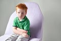 Cute red haired freckled little boy in green t-shirt waiting for doctor in medical office Royalty Free Stock Photo