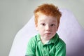 Cute red haired freckled little boy in green t-shirt waiting for doctor in medical office Royalty Free Stock Photo