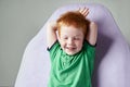 Cute red haired freckled little boy in green t-shirt waiting for doctor in medical office Royalty Free Stock Photo