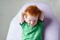 Cute red haired freckled little boy in green t-shirt waiting for doctor in medical office Royalty Free Stock Photo