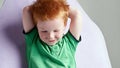 Cute red haired freckled little boy in green t-shirt waiting for doctor in medical office Royalty Free Stock Photo