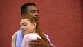 Cute red-haired girl snuggling to her mixed-race boyfriend, couple hugging