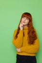 Cute red haired young woman in yellow turtleneck sweater is looking up and thinking Royalty Free Stock Photo