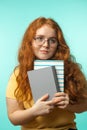 Redhead young woman holding blank books looking at the camera on blue Royalty Free Stock Photo